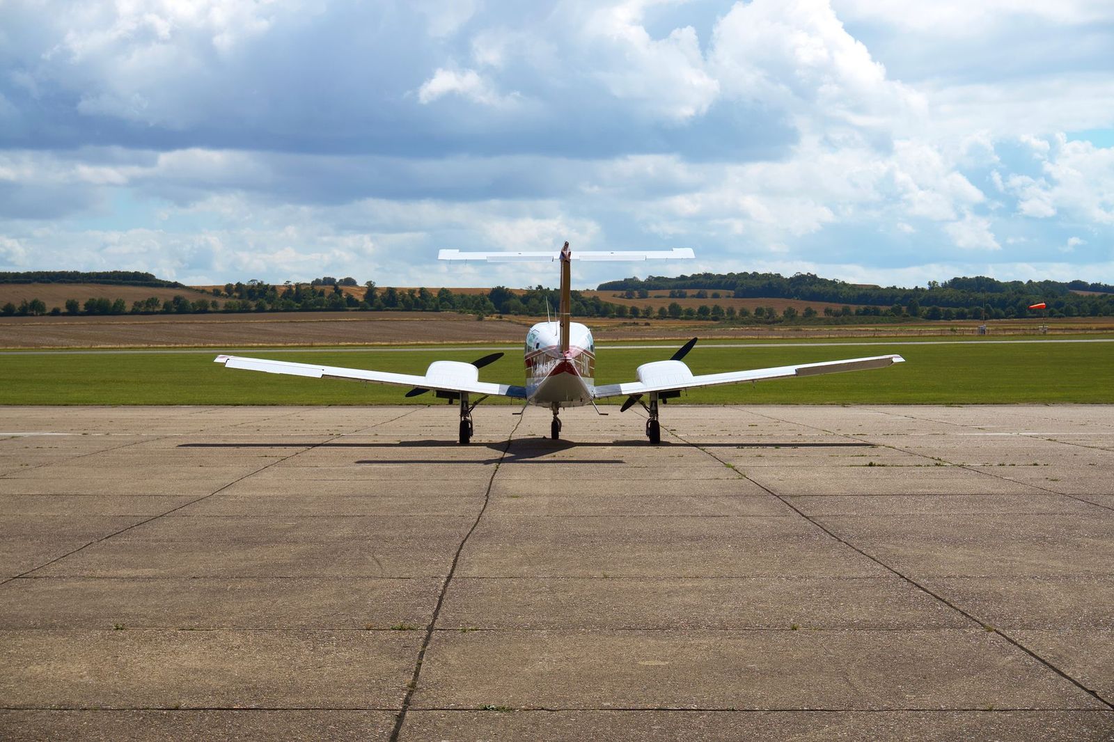 A light aircraft parked on an airfield apron on a summer day, the kind of traffic a general-aviation airport handles