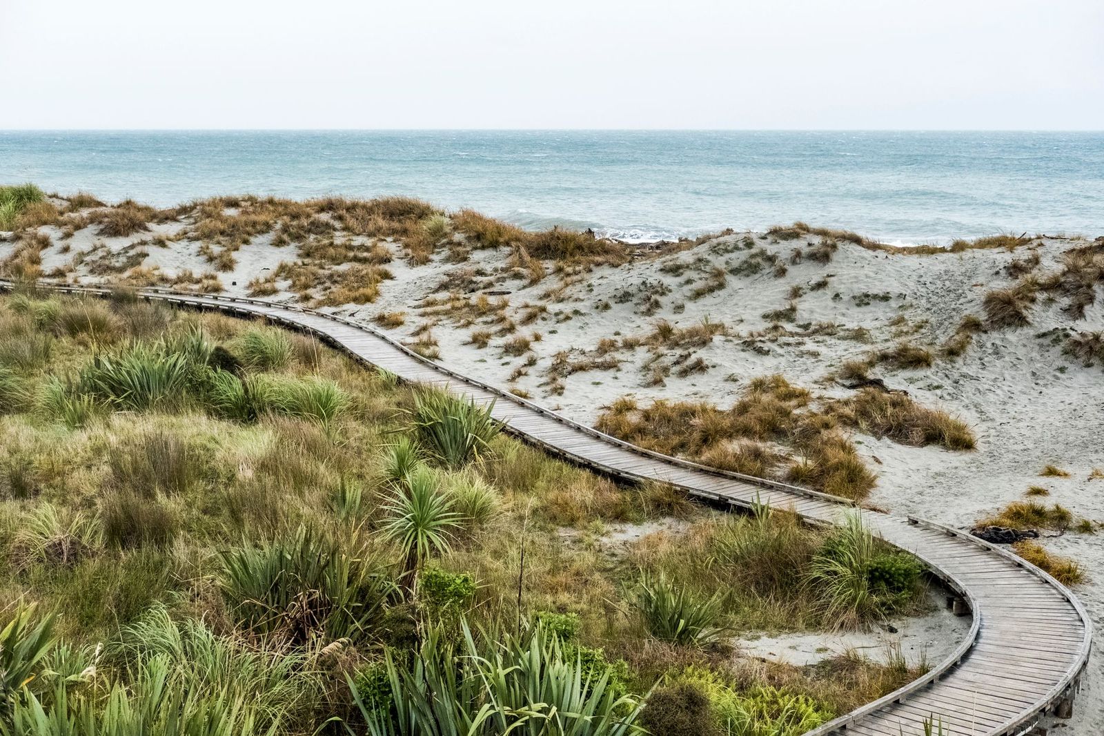 A boardwalk through dune grass, one of the quieter ways to reach the water