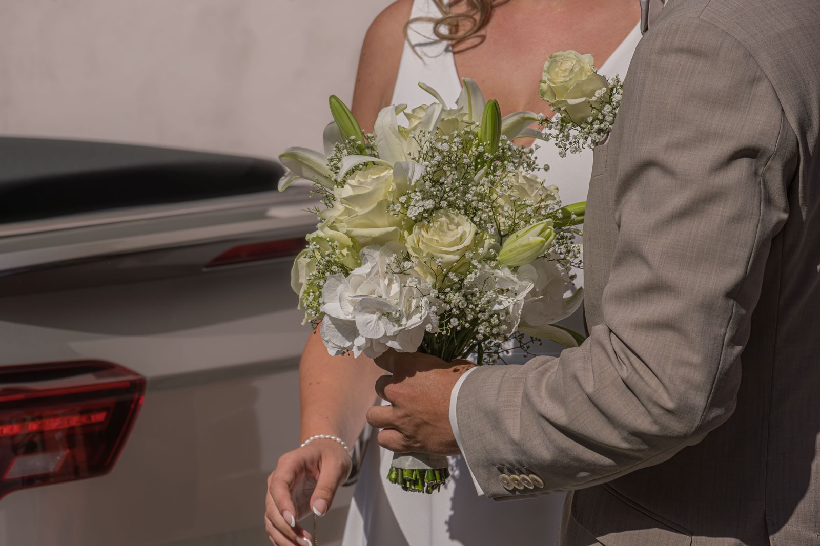A bride and groom walking beside a limousine on the day of a wedding