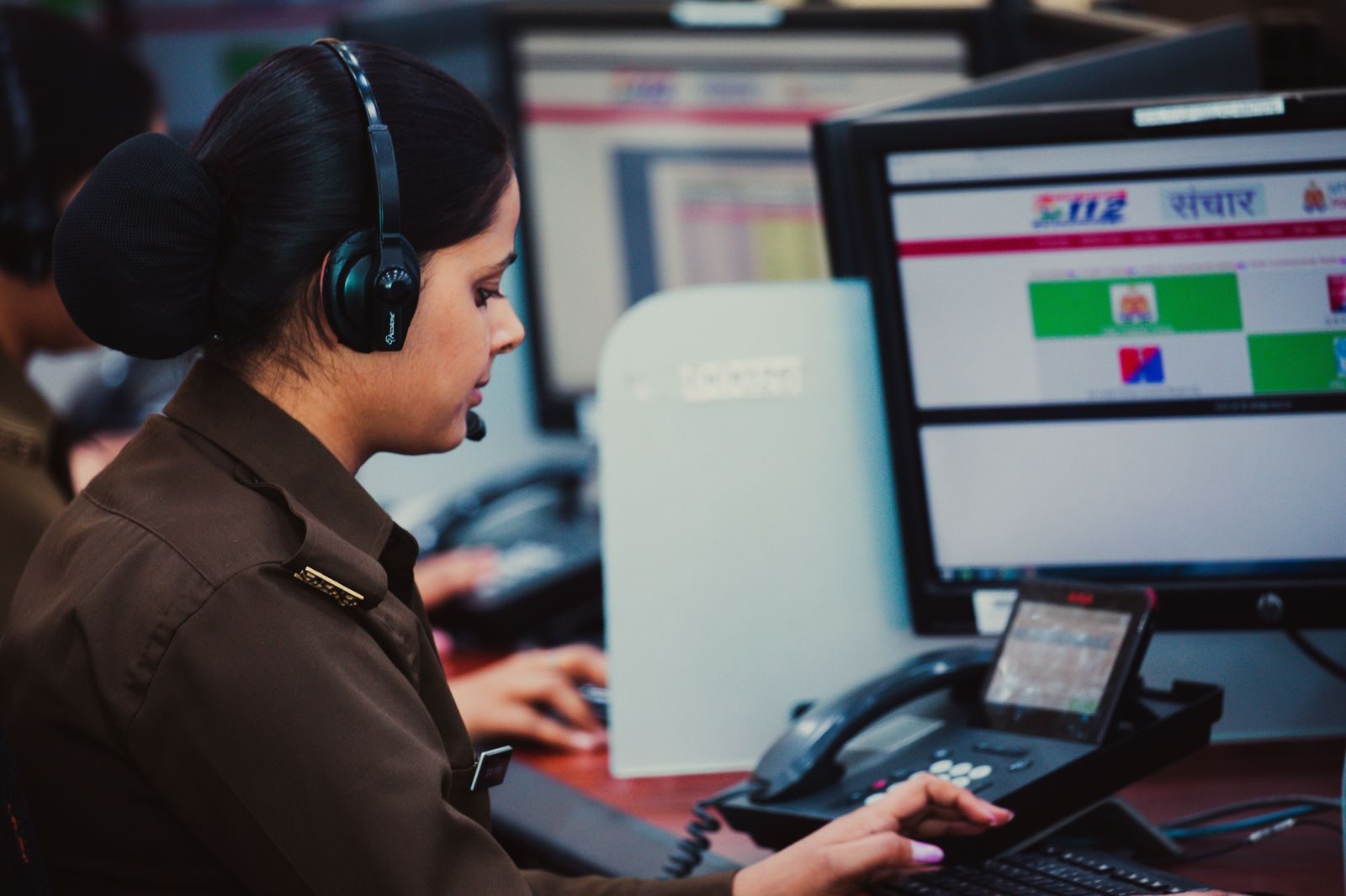 A dispatcher in a headset watching vehicle and flight screens at night
