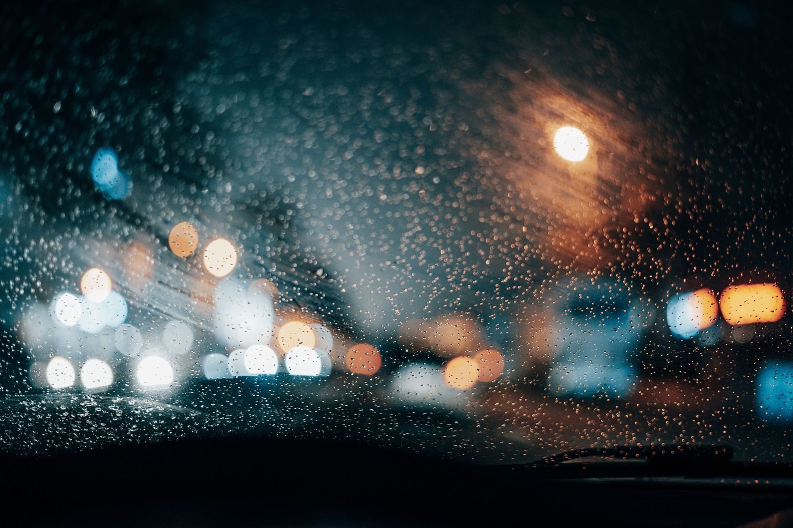 Two children pressed against a car window watching Christmas lights glow outside