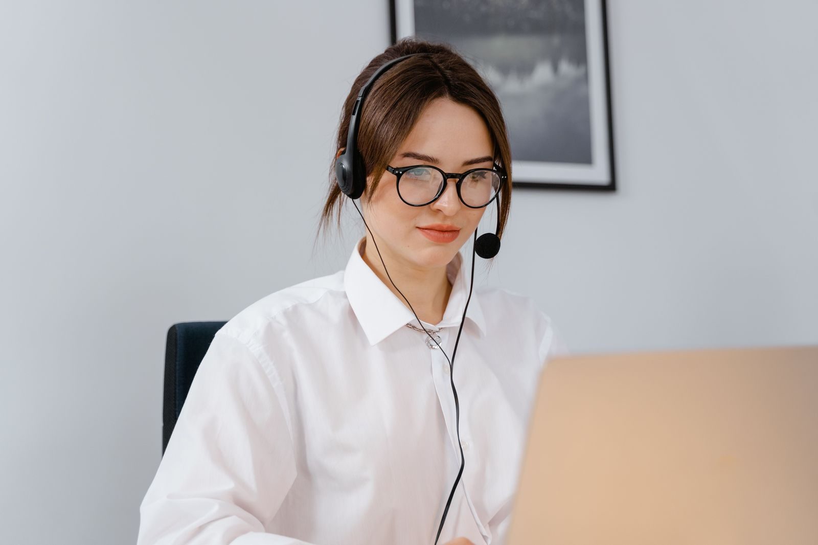 An assistant at a desk arranging travel on a laptop in a bright office