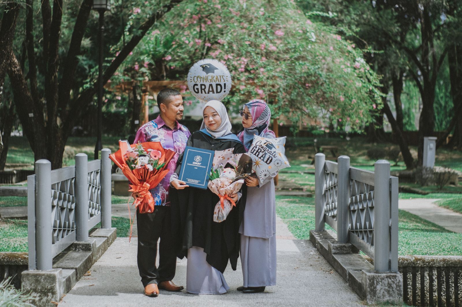 Proud parents hugging a graduate in a gown after a ceremony