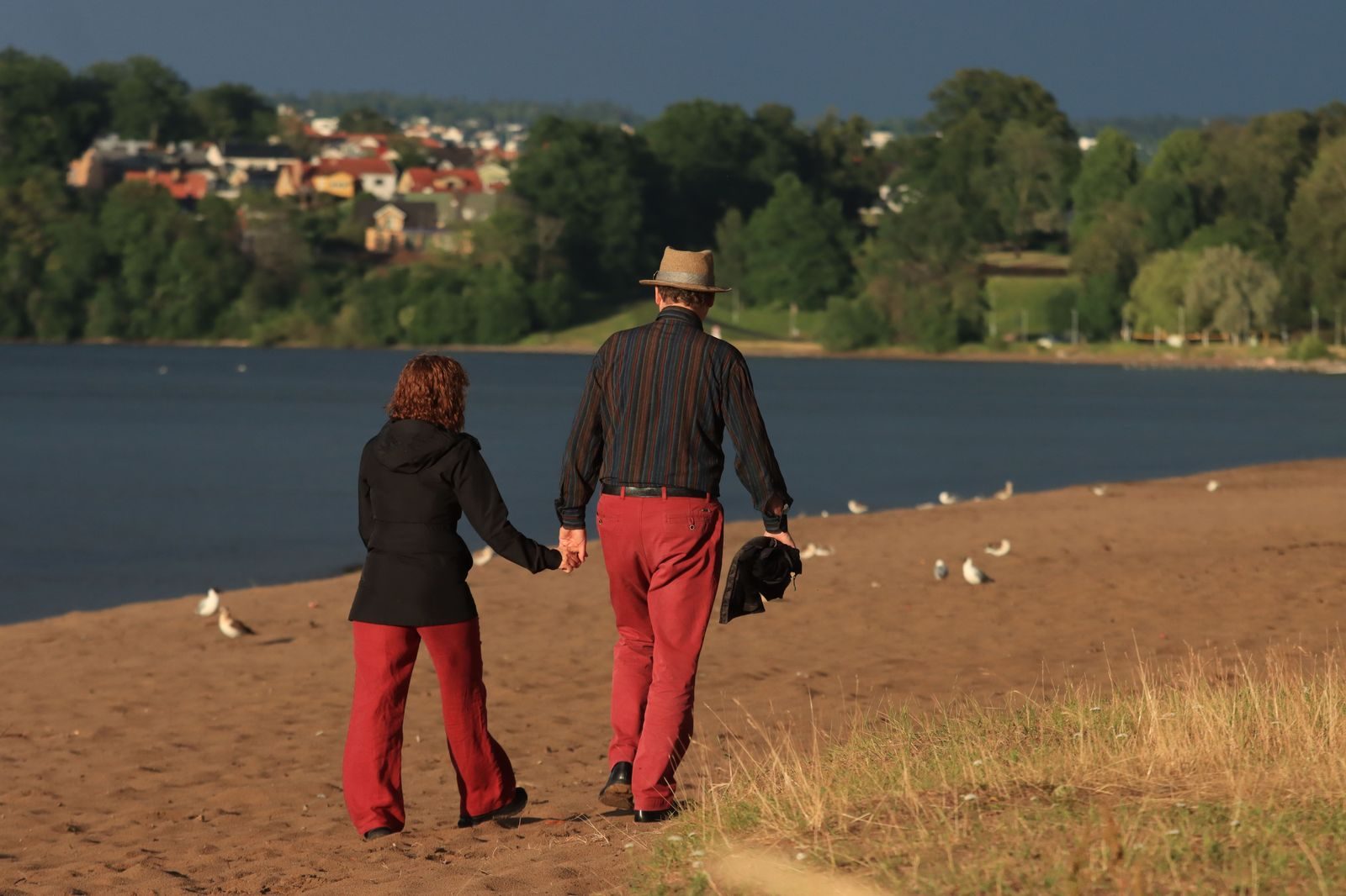 An older couple walking along a lakeside promenade on a sunny day