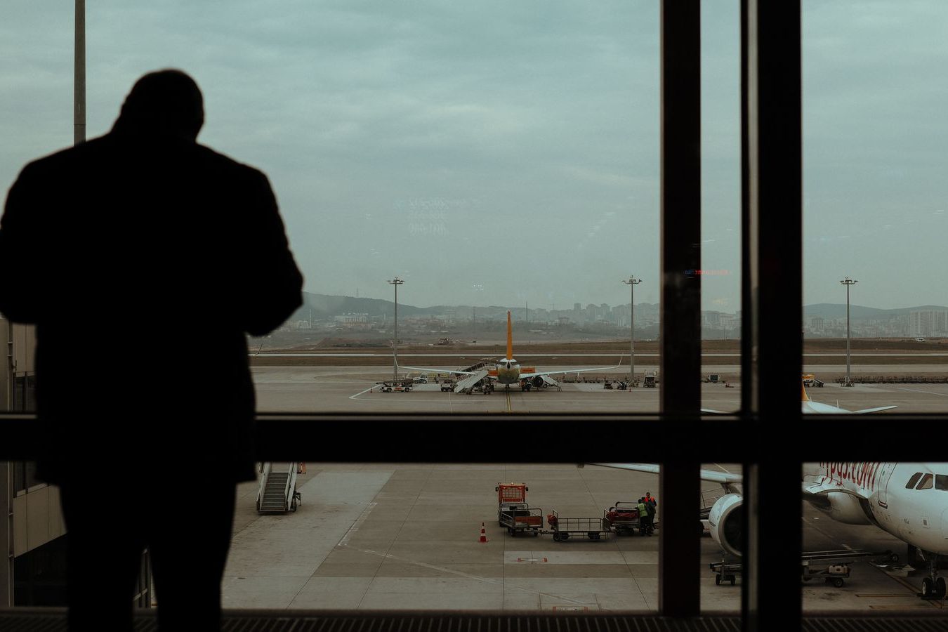A chauffeur waiting at an airport arrivals curb with a name board