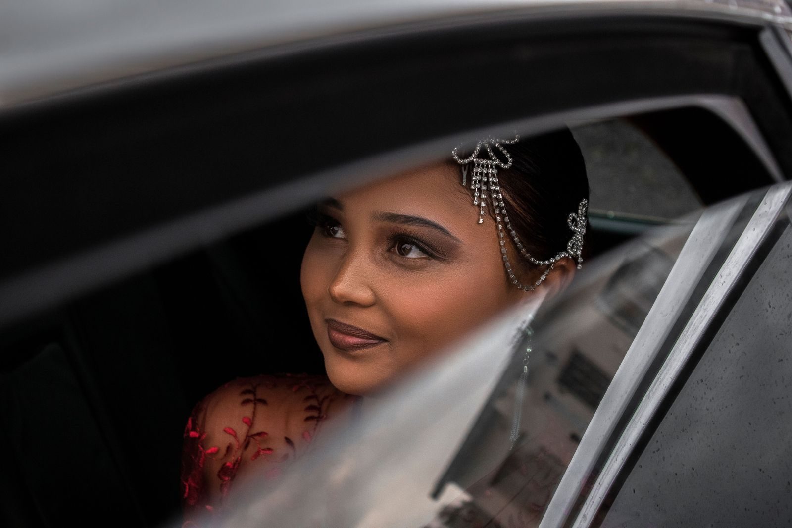 A teenage girl in a long formal dress stepping out of a black car outside a hall