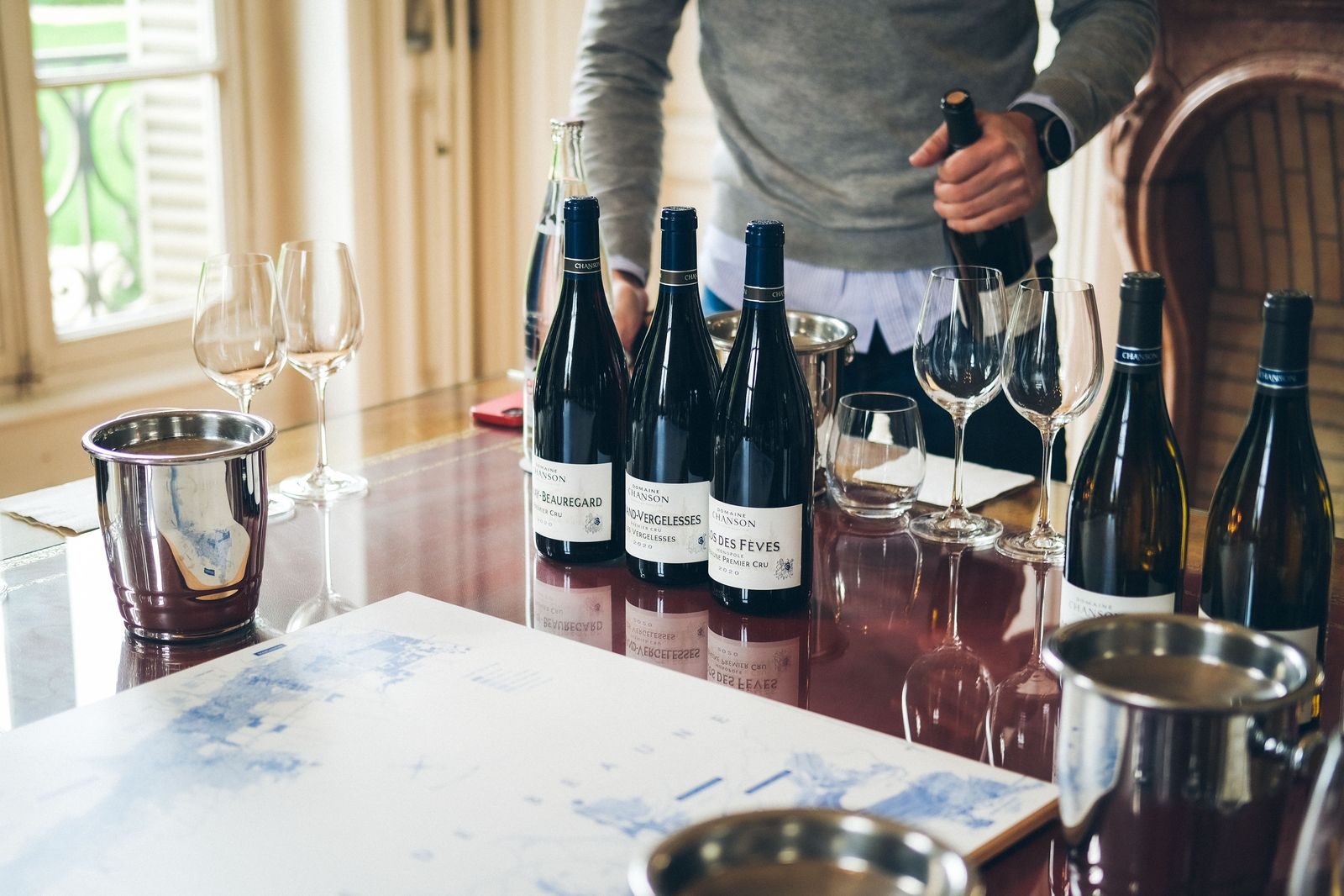 Glasses lined up on a winery tasting counter with vineyard view behind