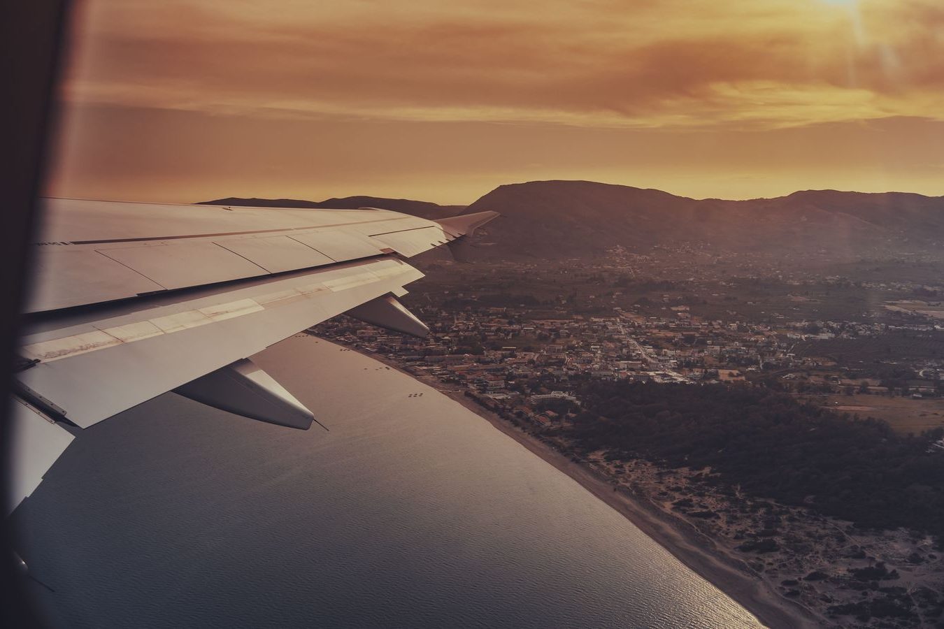 Aircraft wing over clouds at sunrise from a passenger window