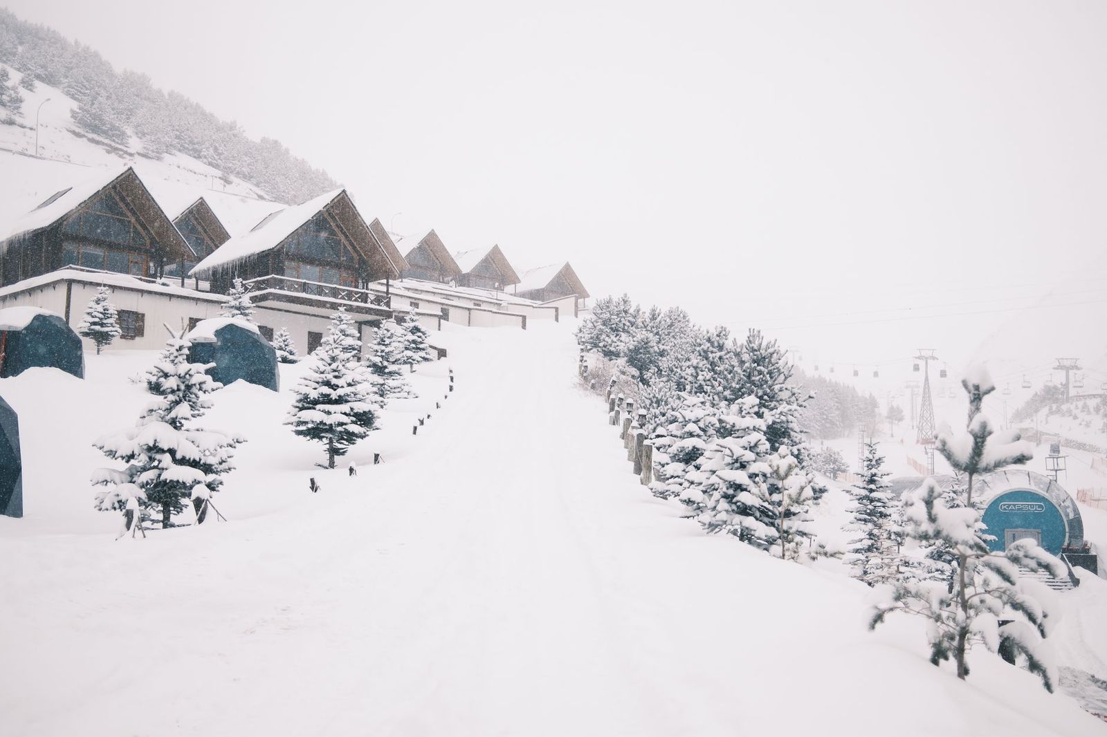 A black SUV waiting for skiers at a snowy resort village drop-off