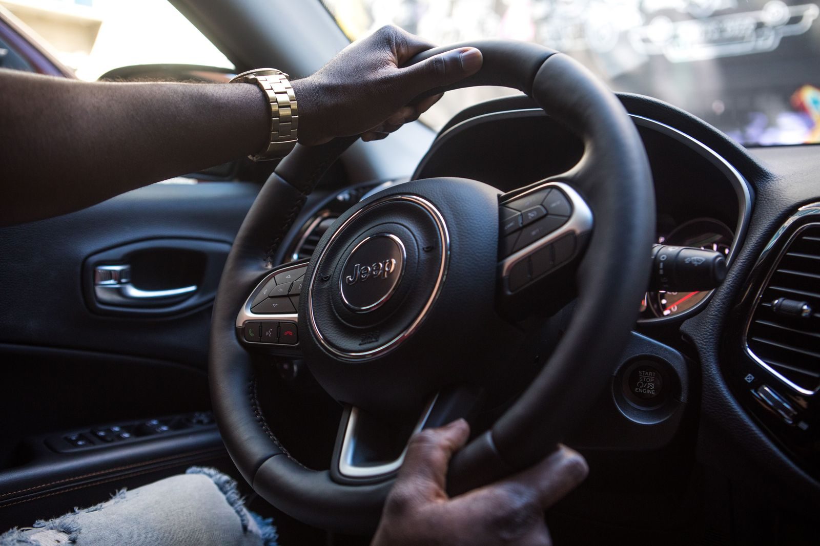 A chauffeur's gloved hands on the steering wheel of a luxury sedan