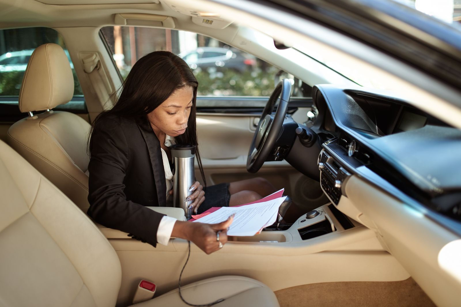 A professional working on a laptop in the back seat of a chauffeured car