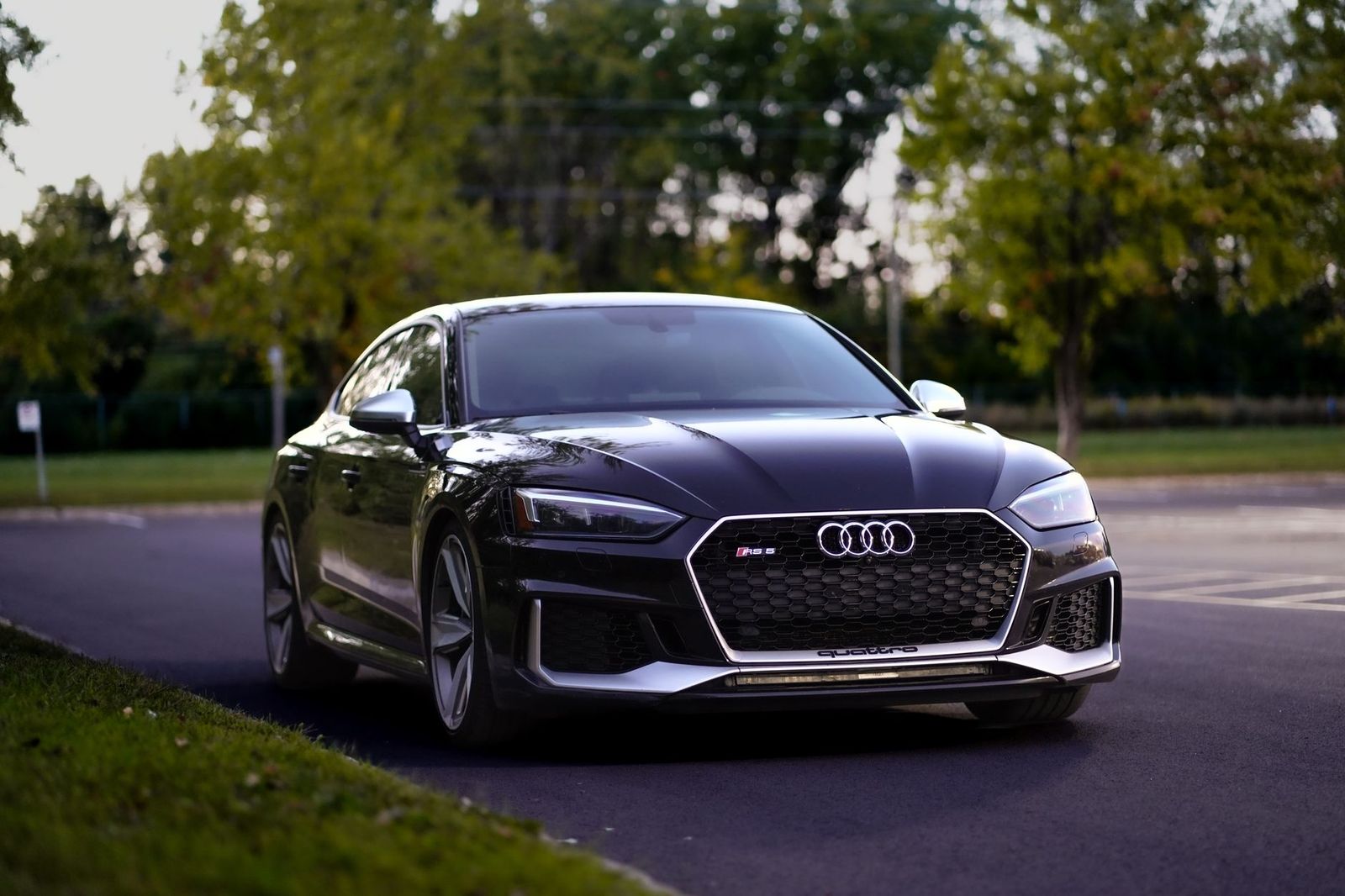 Black business sedan driving along a quiet rural road in summer