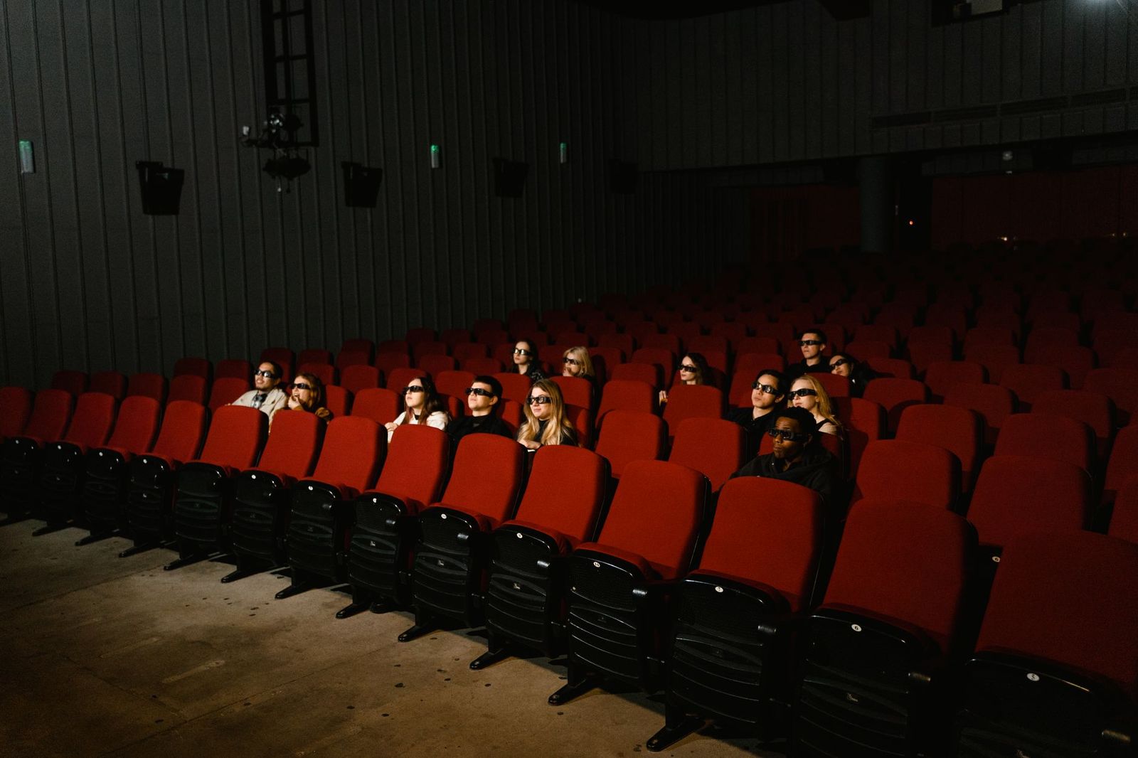 Guests arriving at a film screening with a chauffeured black car waiting at the curb