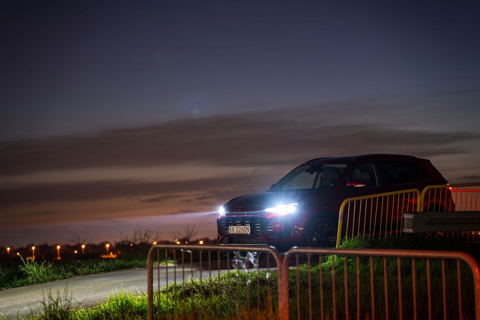 Chauffeur standing beside a black SUV at night near a festival