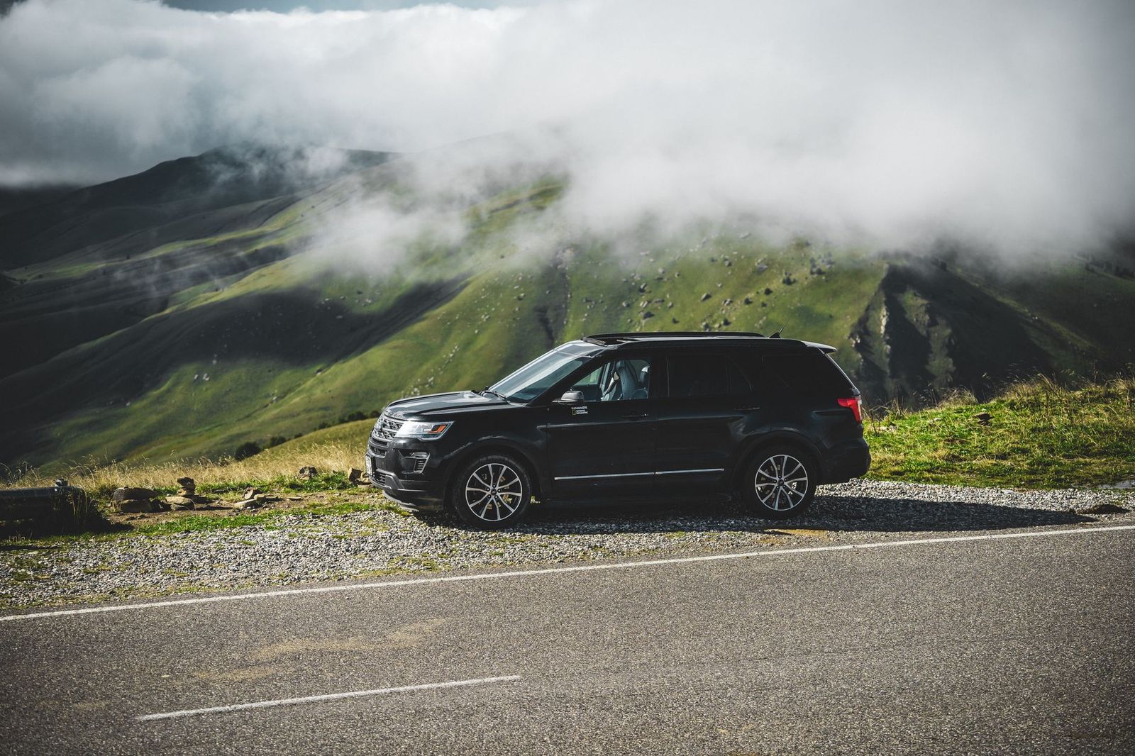 A black SUV on a country road in summer, the kind of car that carries a festival group from Barrie to Orillia