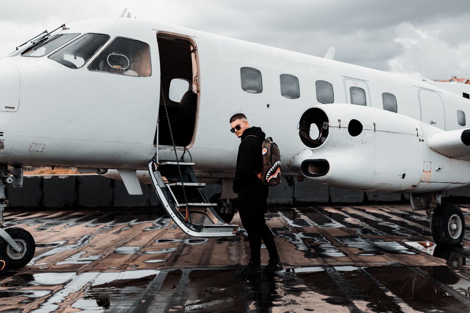 A chauffeur loading luggage into a black sedan beside a private aviation terminal
