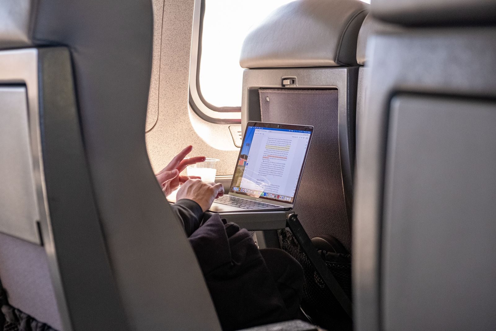 A business traveller reading a booking confirmation on a phone in the back seat of a car