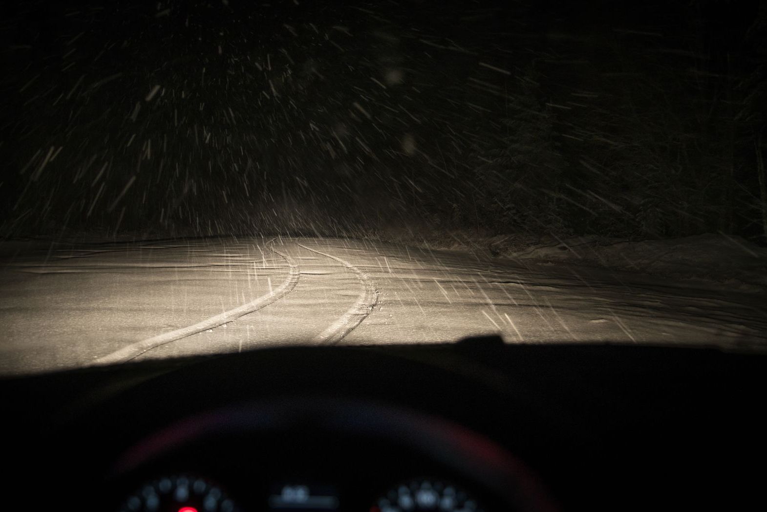Headlights on a highway in falling snow with reduced visibility