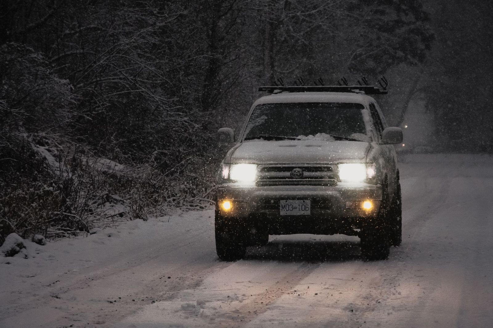 A black SUV driving on a snow-covered country road