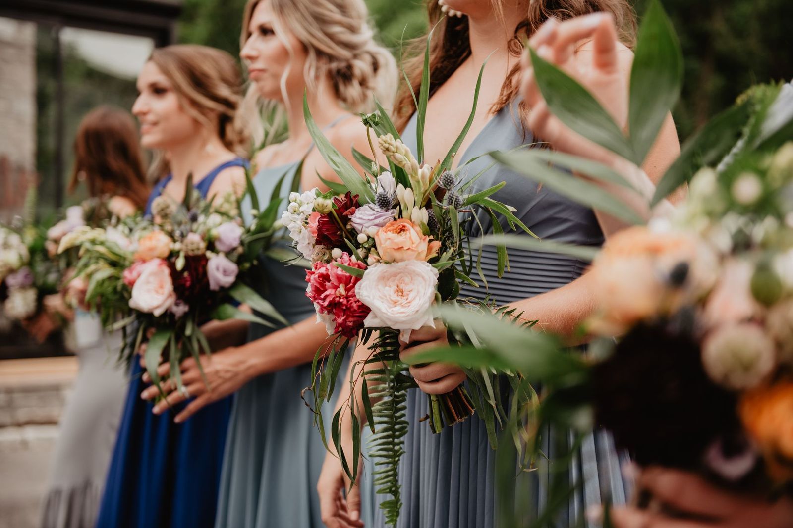 Wedding party with bouquets beside a car