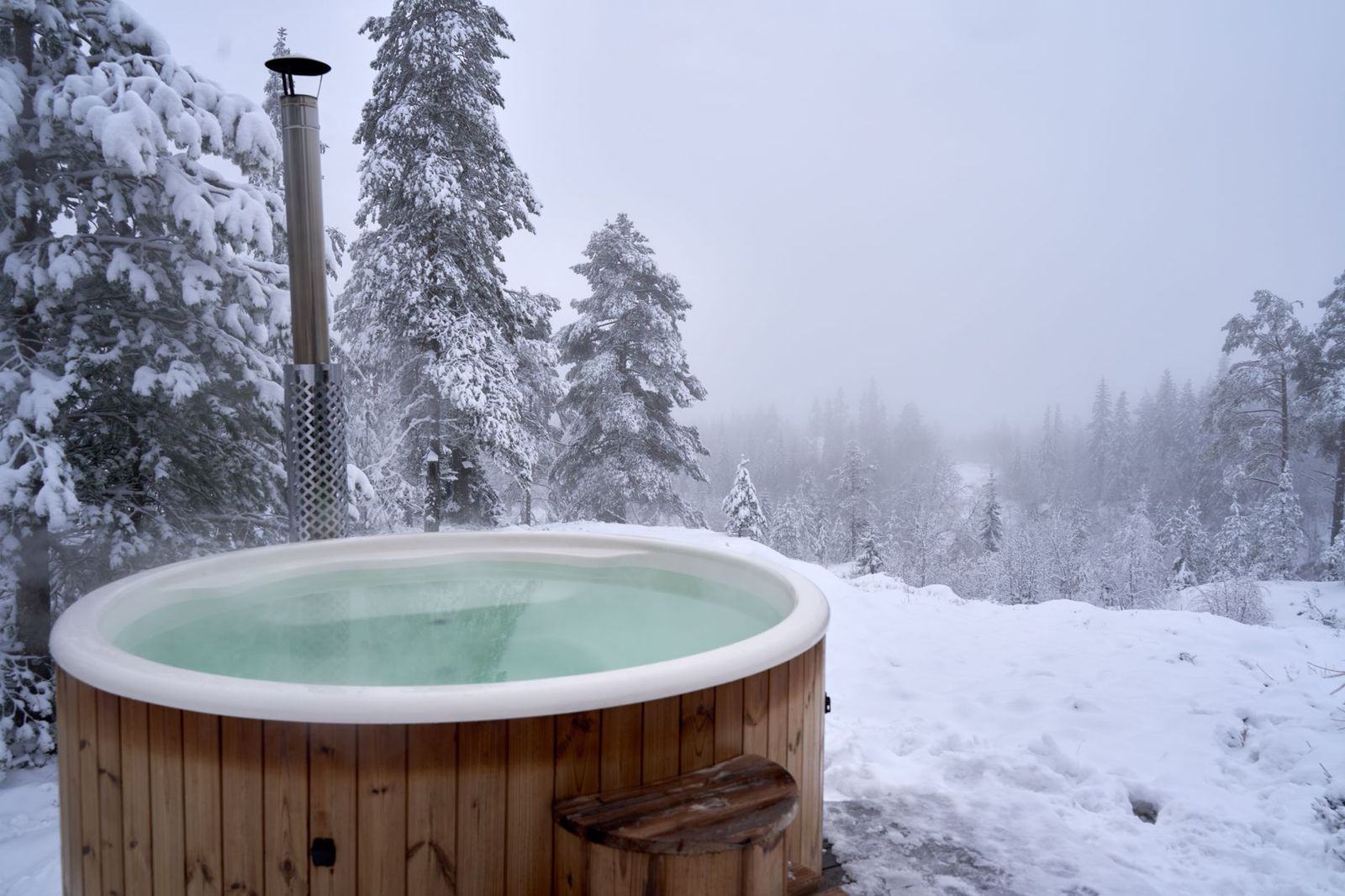 Steam rising from an outdoor Nordic spa pool on a cold winter evening