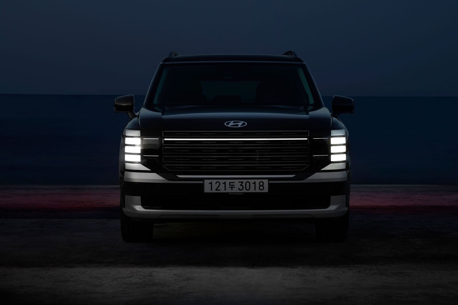 A black SUV waiting at a hotel entrance in the evening
