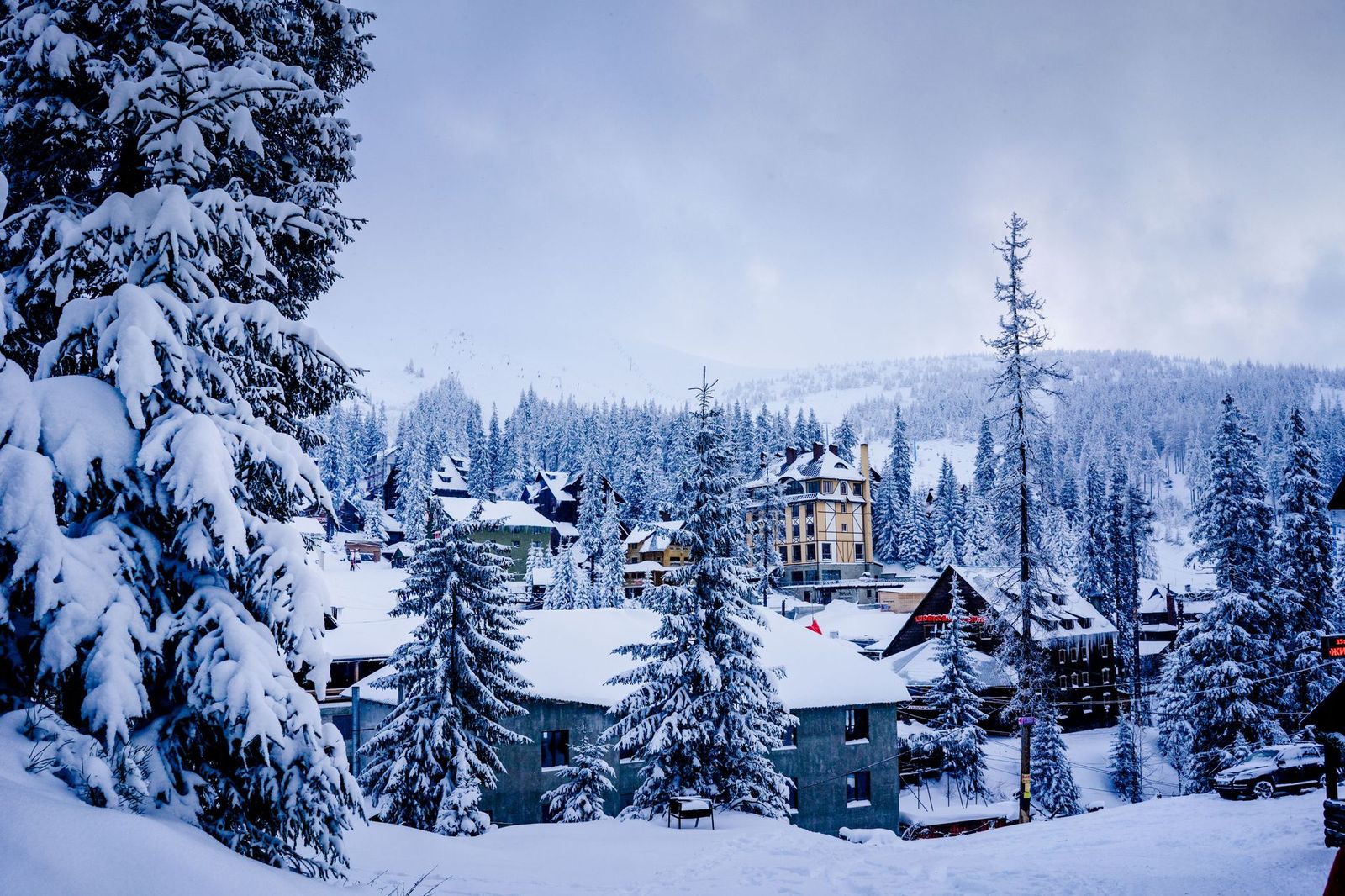 A resort village with warm evening lights at the foot of a ski hill
