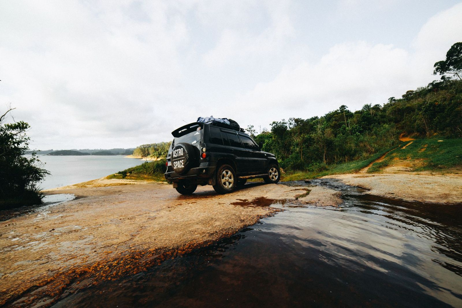 A black SUV parked in a lakeside driveway beside a cottage