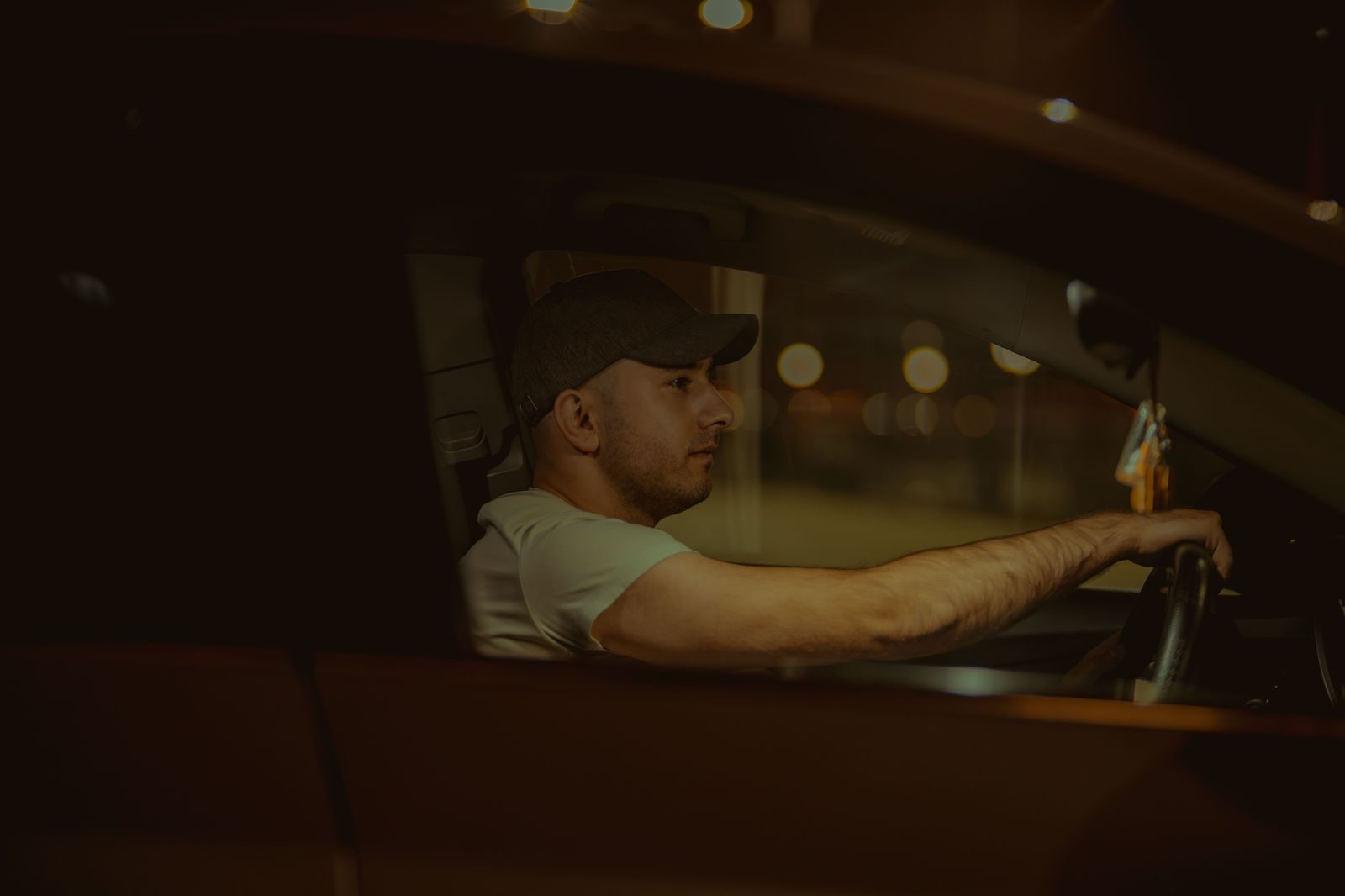 A chauffeur opening the rear door of a black car at night