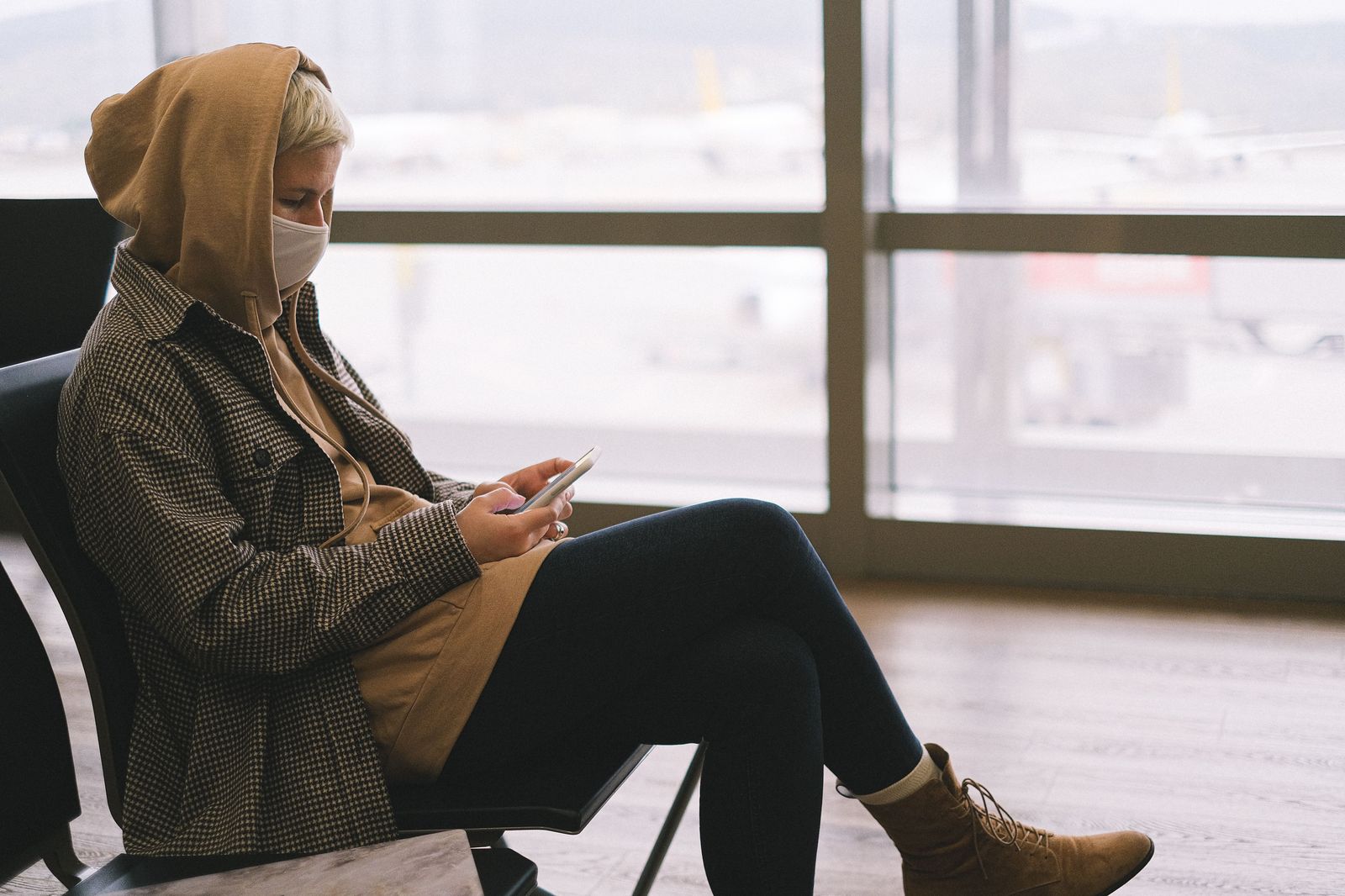 A traveller checking a phone at the departures curb: a booked car with a fixed fare means one less thing to organise on the morning of a flight