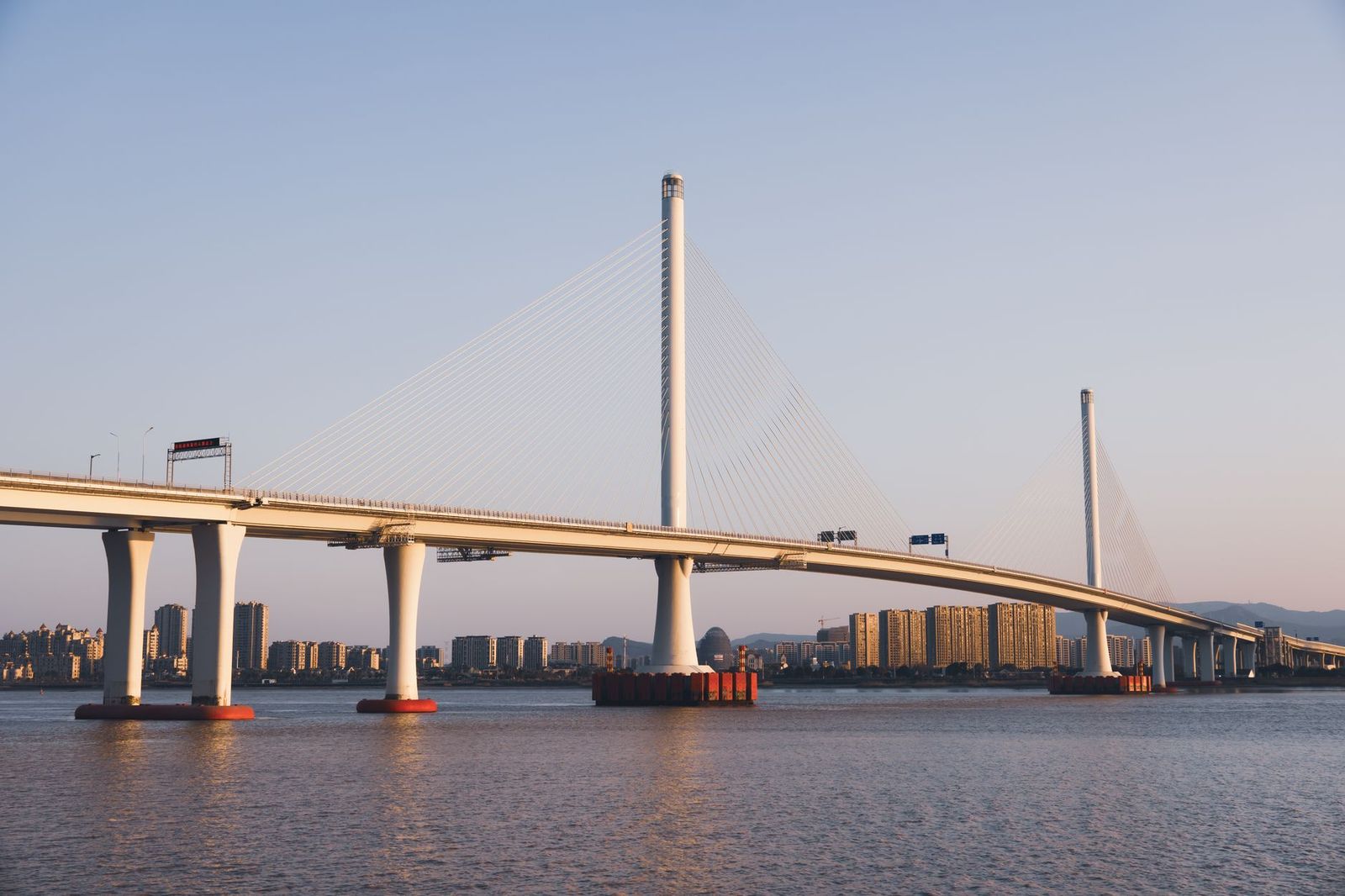 Black sedan approaching a border crossing bridge on a clear day