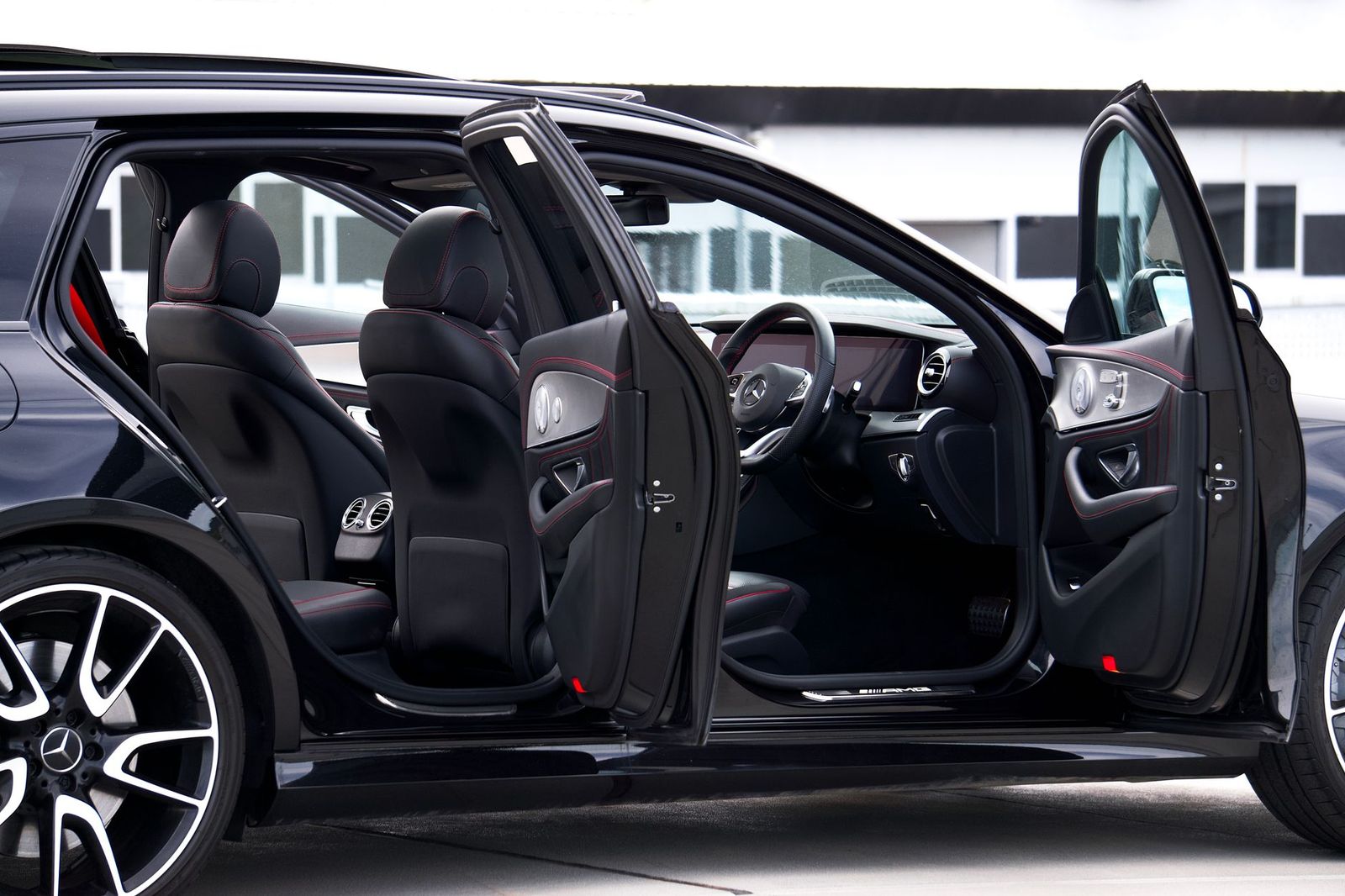 Chauffeur opening the rear door of a black luxury sedan at dusk